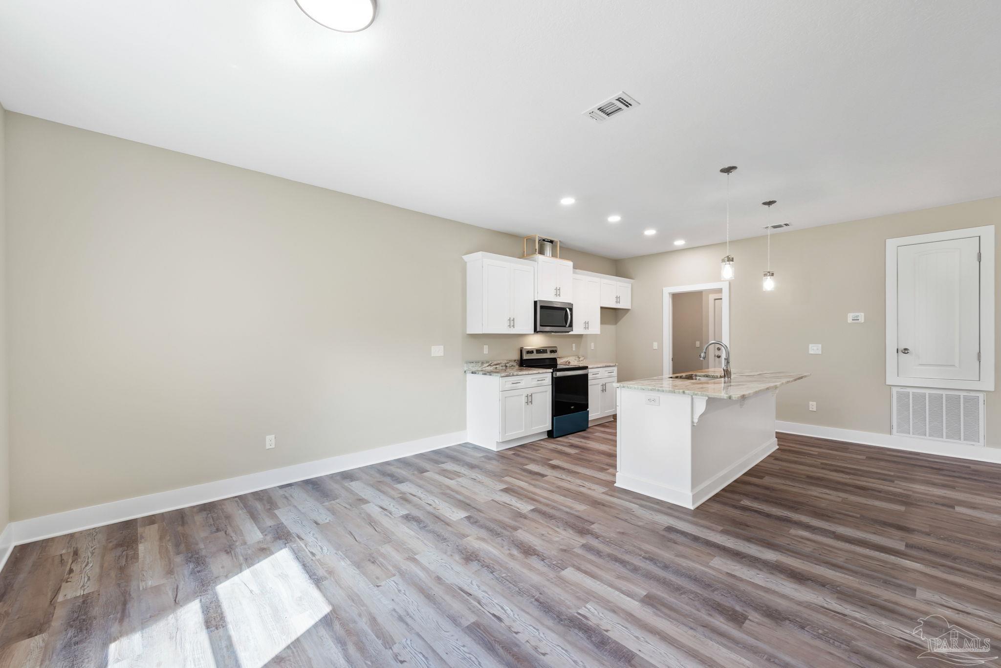 8261 Larson Lane Milton, FL 32583 - Photo 27 of 47 a large white kitchen with wooden floor and stainless steel appliances