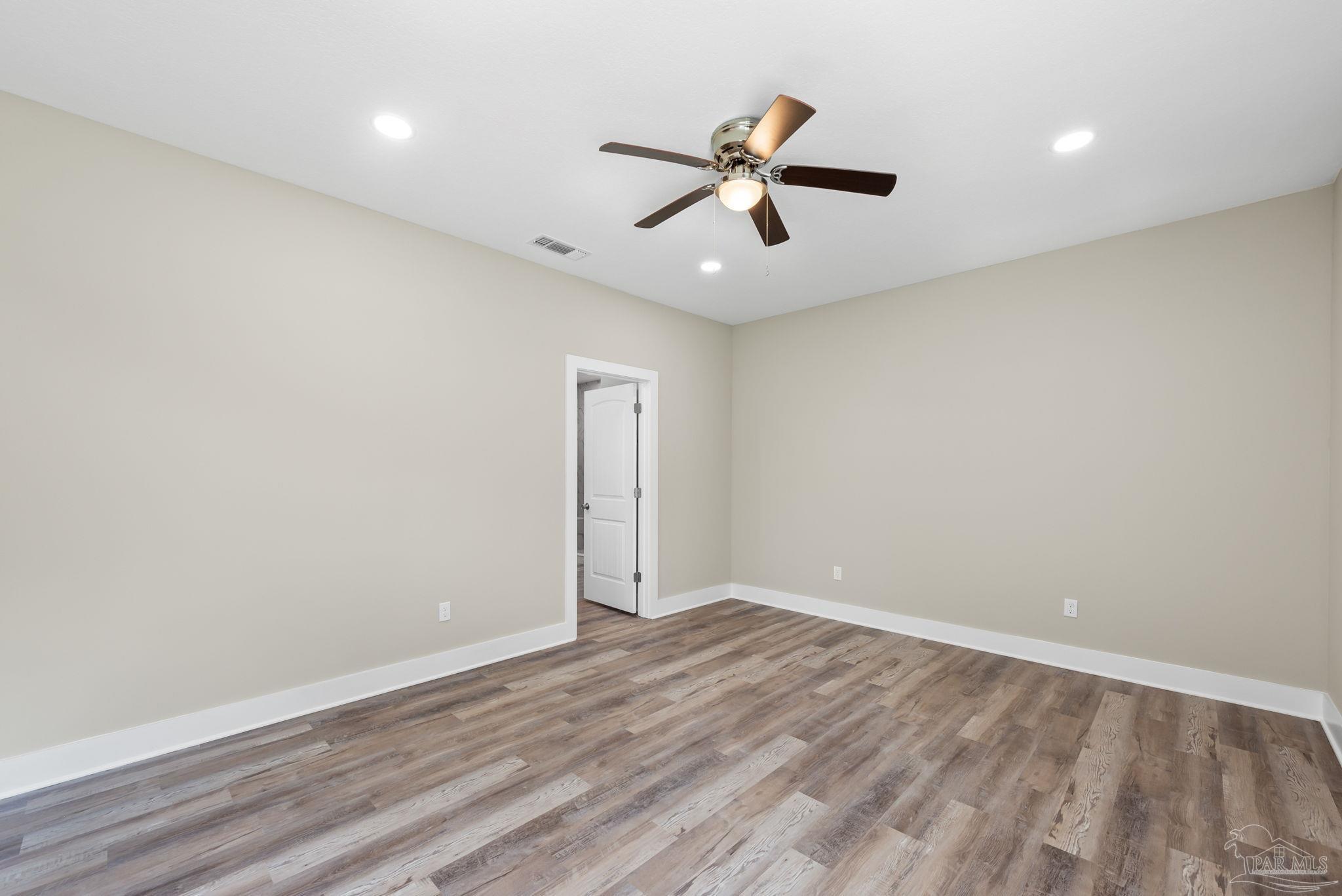 8261 Larson Lane Milton, FL 32583 - Photo 31 of 47 an empty room with wooden floor fan and windows