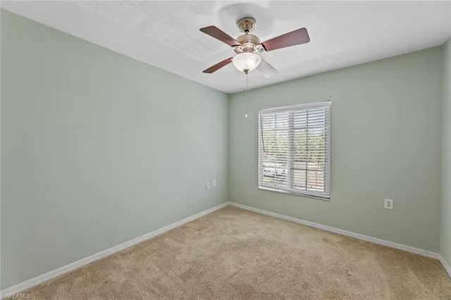 an empty room with a window and a fan