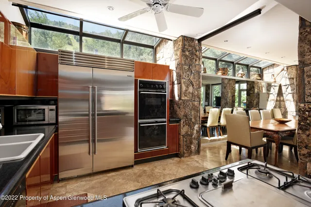 a kitchen with stainless steel appliances granite countertop a refrigerator a stove and a sink with wooden floor