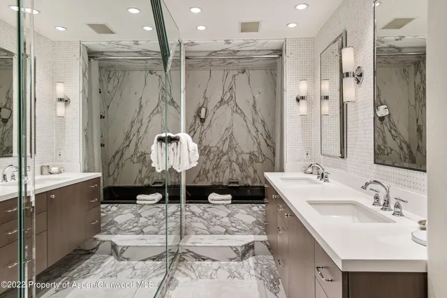 a bathroom with a granite countertop sink a mirror and shower