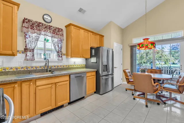 a kitchen with stainless steel appliances kitchen island granite countertop a table chairs in it and wooden floor
