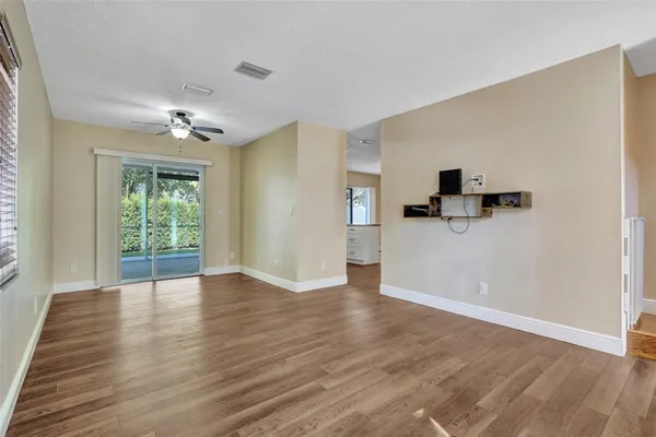 a view of empty room with wooden floor and fan