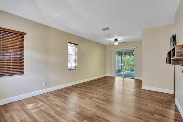 a view of an empty room with a window and wooden floor