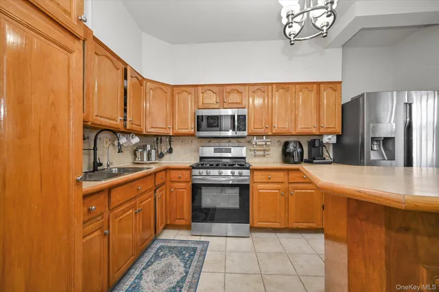 a kitchen with stainless steel appliances granite countertop a sink a stove a refrigerator cabinets and a window