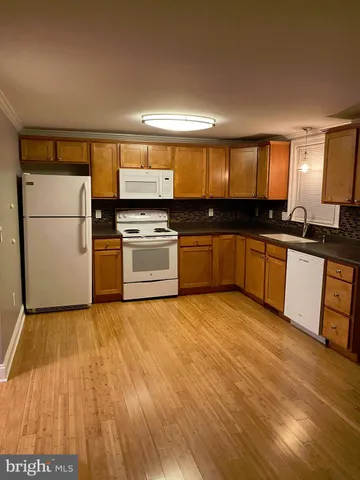 a large kitchen with granite countertop a stove top oven a sink and a refrigerator