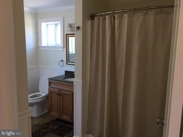 a bathroom with a sink a toilet a mirror and shower curtain