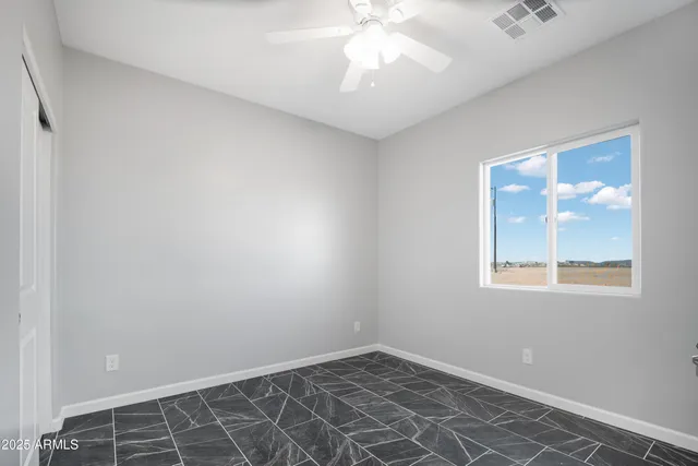 an empty room with a chandelier fan and windows