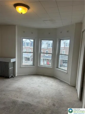 a view of an empty room with a window and chandelier fan