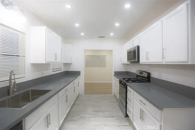 a kitchen with granite countertop white cabinets and stainless steel appliances