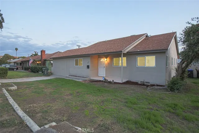 a backyard of a house with plants and large tree