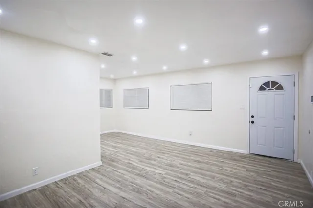 an empty room with wooden floor and windows