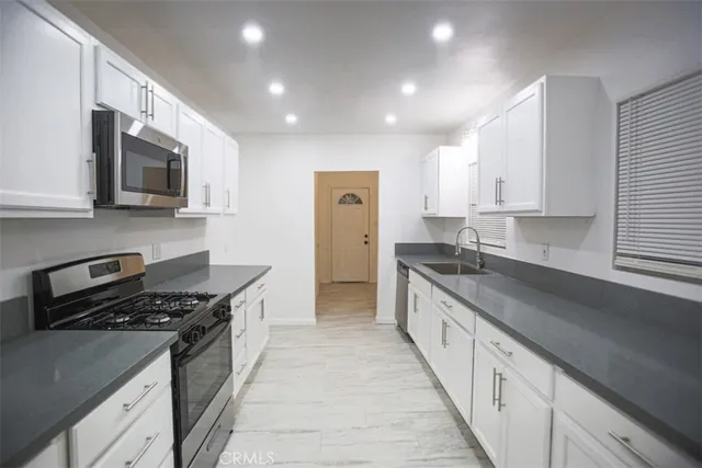 a large kitchen with stainless steel appliances granite countertop a stove a sink and a microwave