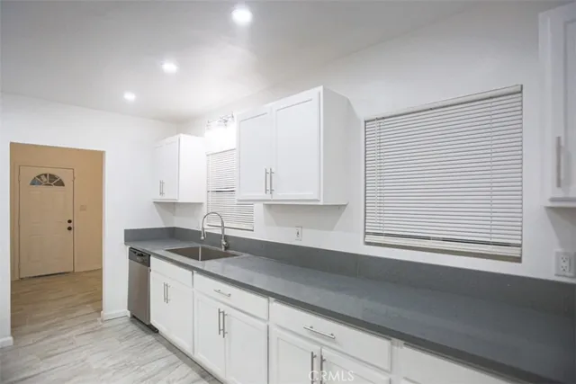a kitchen with granite countertop white cabinets and a sink