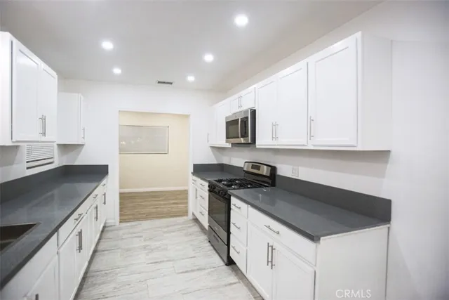 a kitchen with granite countertop white cabinets and appliances