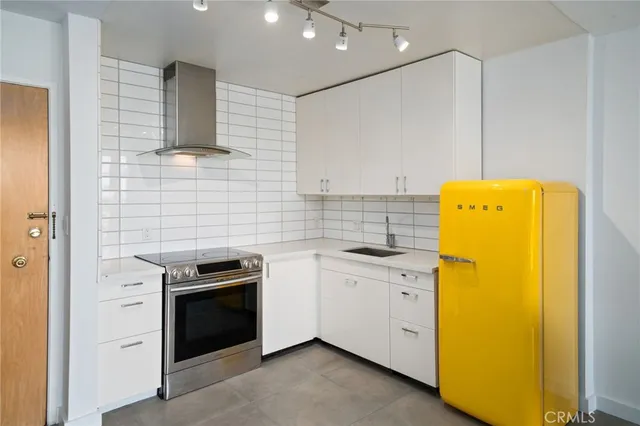 a kitchen with stainless steel appliances a stove a sink and white cabinets