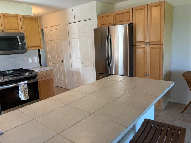 a kitchen with granite countertop a refrigerator and a stove top oven