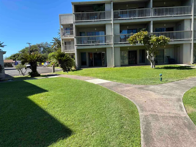 a front view of a house with a yard and potted plants