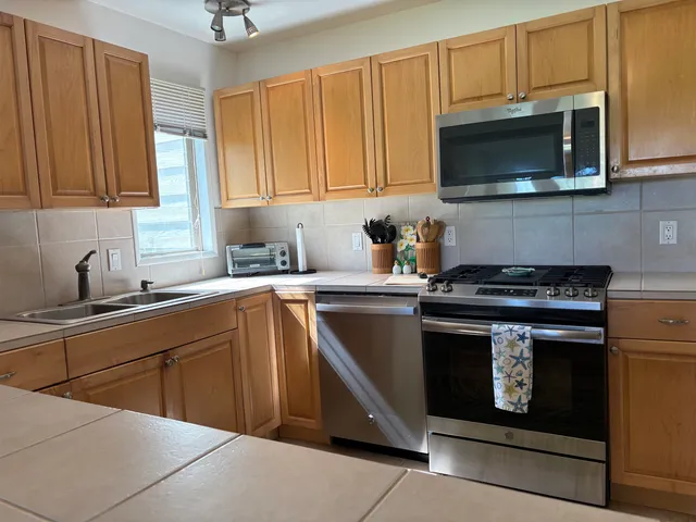 a kitchen with stainless steel appliances granite countertop a stove microwave and sink