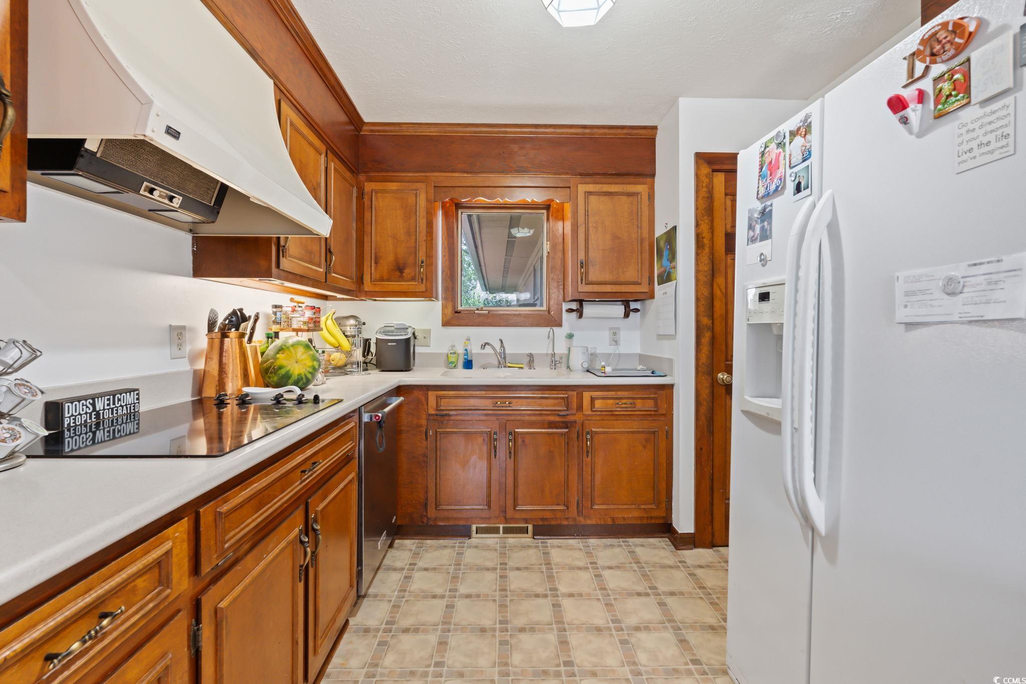 3533 Lighthouse Way Myrtle Beach, SC 29577 - Photo 17 of 40 Kitchen with white fridge with ice dispenser, under cabinet range hood, black electric cooktop, light countertops, and light flooring