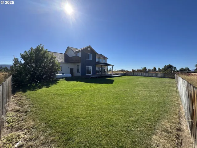 a view of a house with a yard and a large tree
