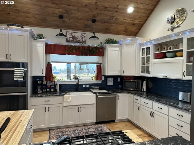 a kitchen with white cabinets a sink a stove and a window