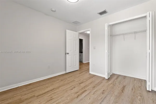 an empty room with wooden floor & closet area