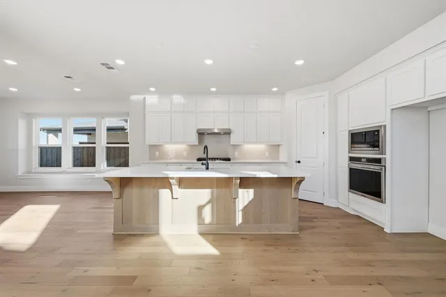 a large kitchen with kitchen island a sink a stove a refrigerator and white cabinets