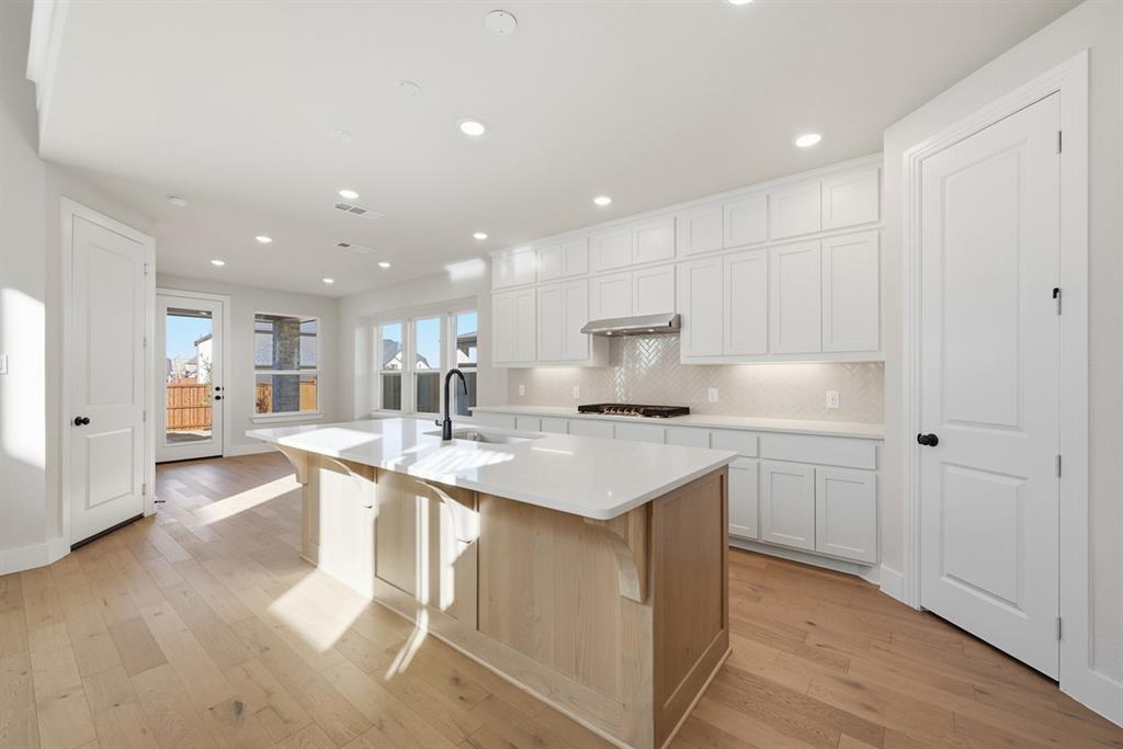 4409 Script Street Prosper, TX 75078 - Photo 3 of 24 a kitchen with kitchen island a sink and a stove top oven