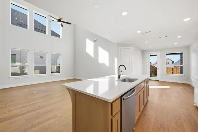 a living room with stainless steel appliances granite countertop a sink and a wooden floor