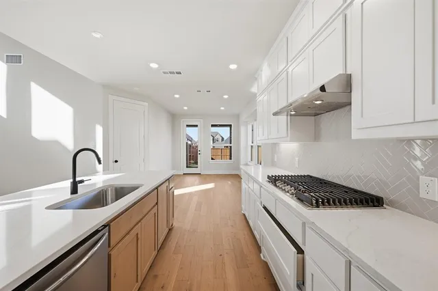 a kitchen with stainless steel appliances a sink a stove and a wooden floors