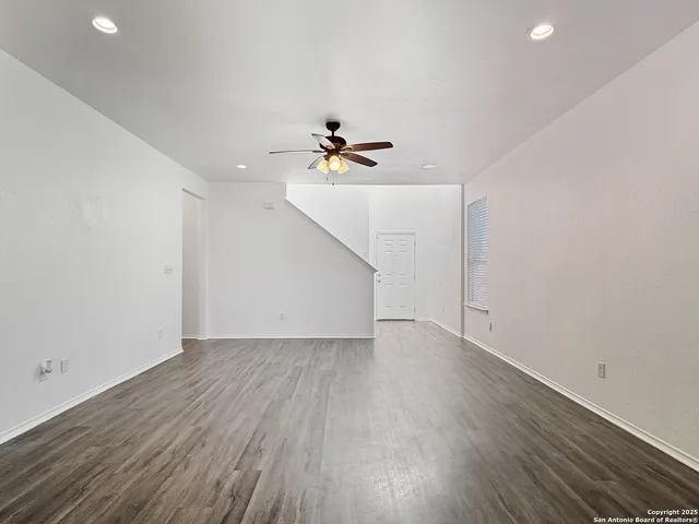 an empty room with wooden floor and ceiling fan