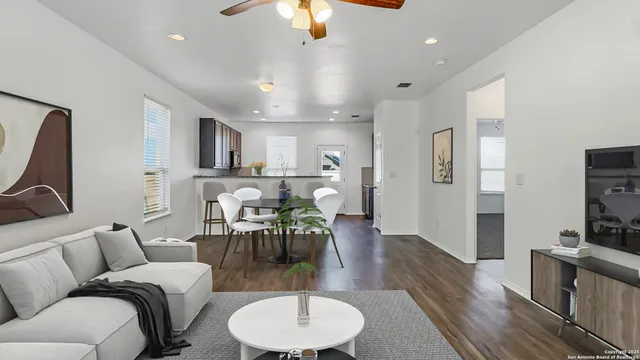 a living room with furniture kitchen view and a wooden floor