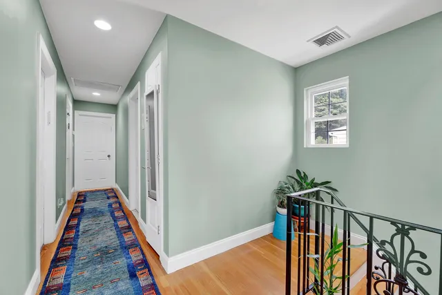 a view of a hallway with wooden floor and stairs