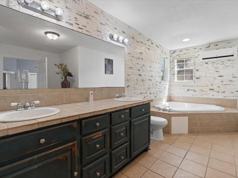 809 East Adams Street Itasca, TX 76055 - Photo 17 of 31 a spacious bathroom with a granite countertop sink a toilet mirror and bathtub
