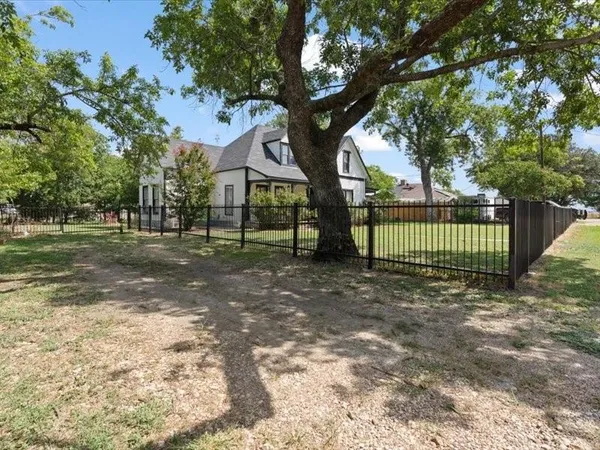 a view of a yard in front of a house with large trees