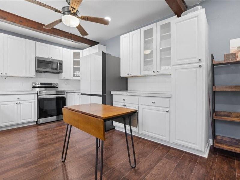 809 East Adams Street Itasca, TX 76055 - Photo 22 of 31 a kitchen with stainless steel appliances granite countertop a stove a refrigerator a microwave a sink and white cabinets with wooden floor