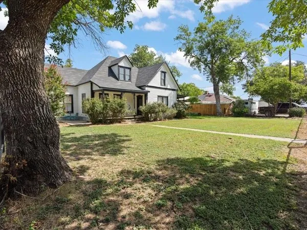 a view of a big house with a big yard and large trees