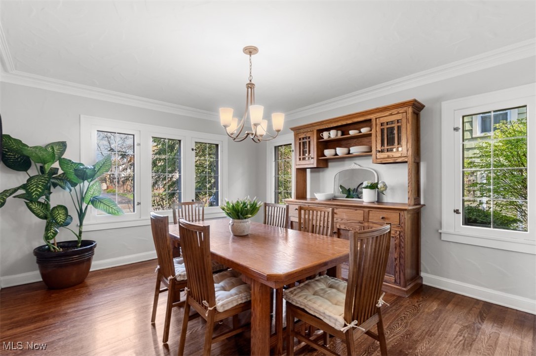 3124 Warrington Road Cleveland, OH 44120 - Photo 8 of 36 Dining space with ornamental molding, baseboards, dark wood-style flooring, and an inviting chandelier