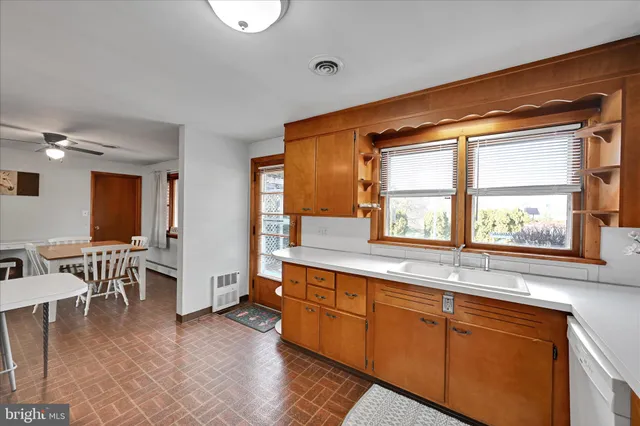 a large white kitchen with cabinets a sink a window and a dining table