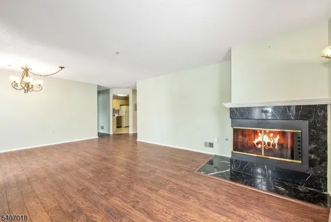 a view of an empty room with a fireplace and wooden floor