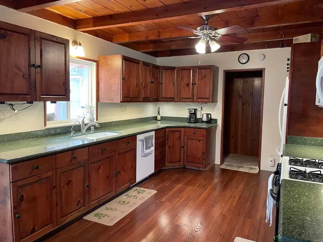 a kitchen with stainless steel appliances granite countertop wooden cabinets a sink and dishwasher with wooden floor