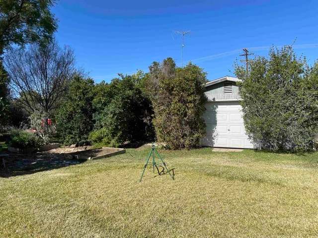 a white house with a big yard and large trees