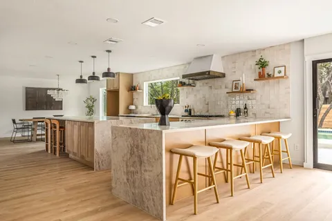 a kitchen with stainless steel appliances kitchen island granite countertop a table and chairs in it