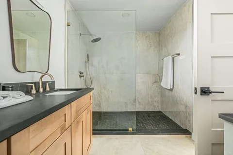 a bathroom with a granite countertop shower sink and mirror