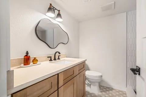 a bathroom with a toilet sink vanity and mirror