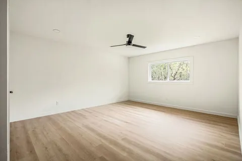 an empty room with a window and a ceiling fan