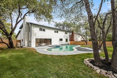 a front view of a house with garden and trees