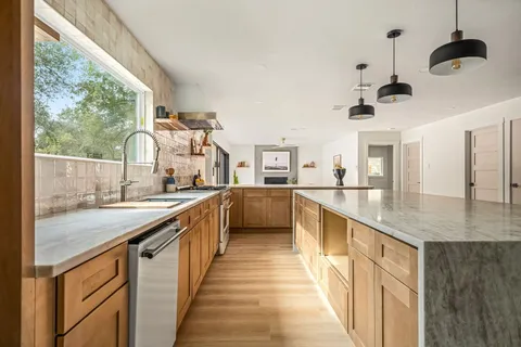 a kitchen with stainless steel appliances granite countertop lots of counter space and windows