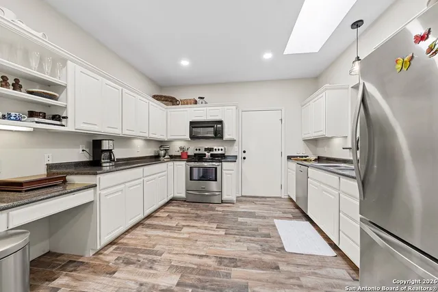 a kitchen with granite countertop a refrigerator stove top oven and sink